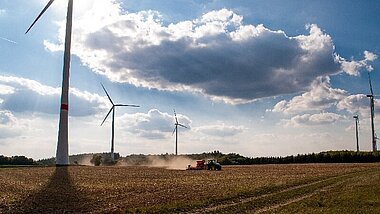 Feld mit Windenergieanlagen wird gemäht